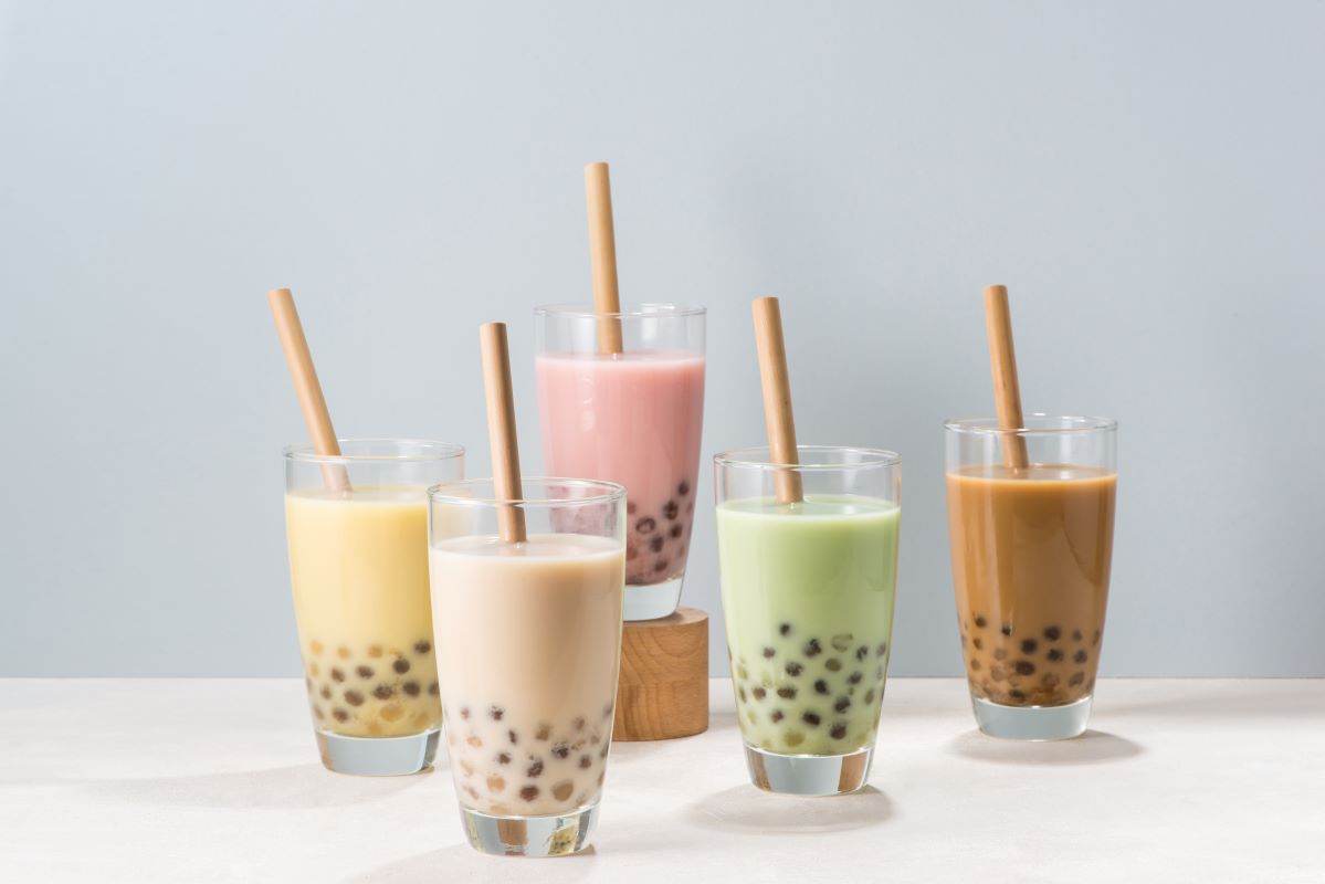 Five glasses of bubble tea with different flavors on a light gray background