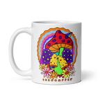 A white ceramic mug with a colorful design featuring smiling mushrooms and flowers in vibrant rainbow colors.